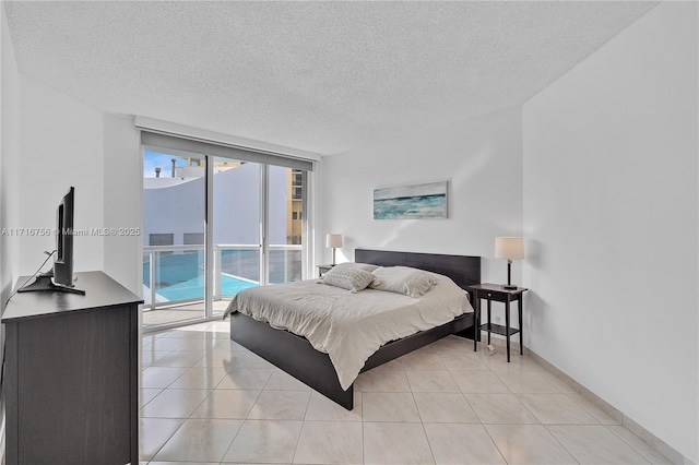 tiled bedroom featuring expansive windows, a textured ceiling, and access to outside