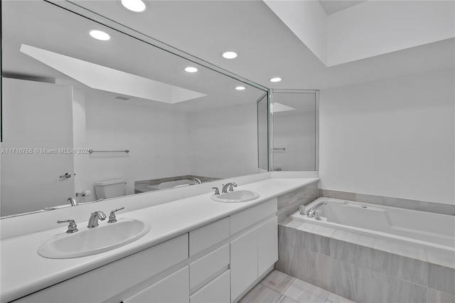 bathroom featuring tiled bath, tile patterned flooring, vanity, and toilet