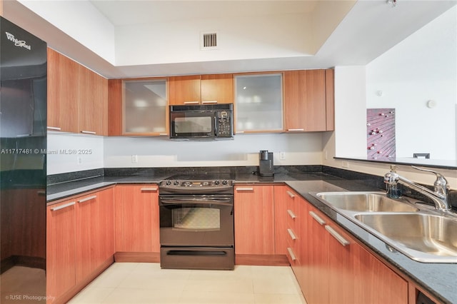 kitchen featuring dark stone counters, sink, light tile patterned floors, and black appliances