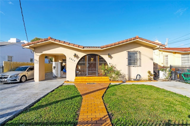 mediterranean / spanish house featuring a carport and a front lawn