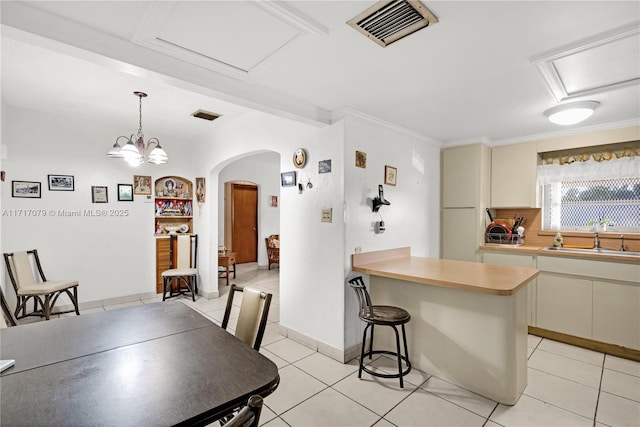 dining area with light tile patterned floors, crown molding, a notable chandelier, and sink