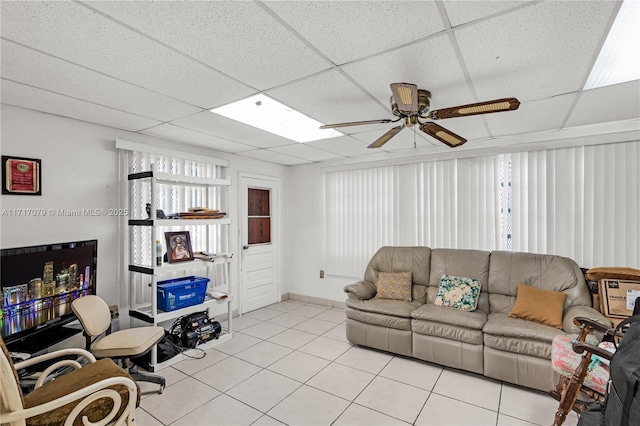 living room featuring light tile patterned floors, a drop ceiling, and ceiling fan