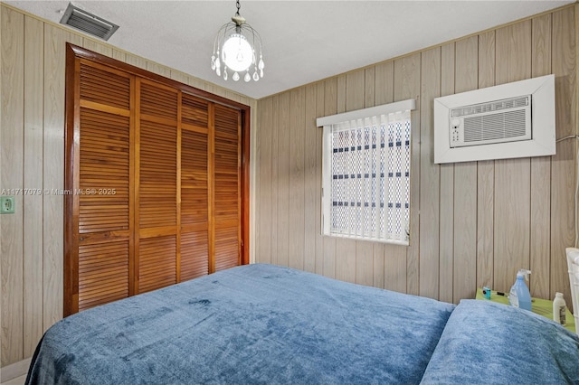 bedroom featuring a wall unit AC, wood walls, and a closet