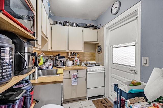 kitchen with white cabinets, sink, decorative backsplash, light tile patterned flooring, and white range oven