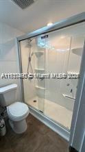 bathroom featuring an enclosed shower and toilet