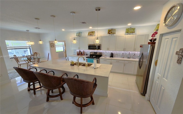 kitchen with pendant lighting, a center island with sink, white cabinetry, and appliances with stainless steel finishes