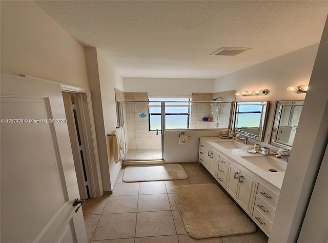 bathroom featuring tile patterned floors, a textured ceiling, plenty of natural light, and an enclosed shower