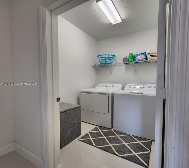 laundry area featuring separate washer and dryer, light tile patterned flooring, and a textured ceiling