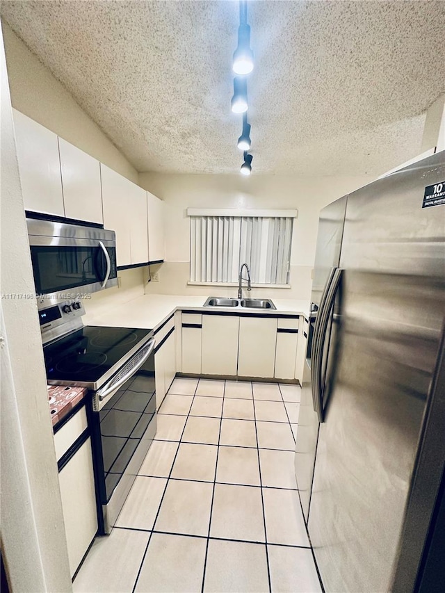 kitchen featuring light tile patterned floors, white cabinetry, sink, and appliances with stainless steel finishes