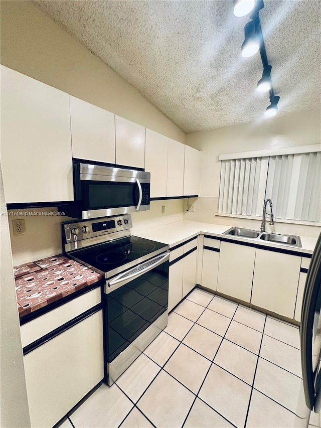 kitchen featuring appliances with stainless steel finishes, track lighting, a textured ceiling, sink, and white cabinets