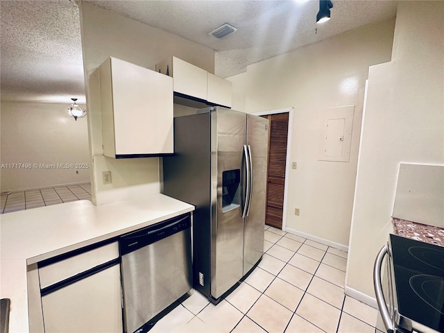 kitchen featuring light tile patterned flooring, electric panel, a textured ceiling, white cabinets, and appliances with stainless steel finishes