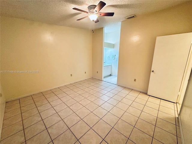 empty room featuring light tile patterned floors, a textured ceiling, and ceiling fan