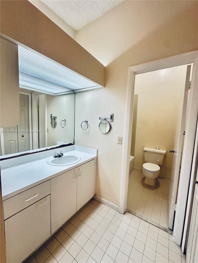 bathroom with tile patterned flooring, a textured ceiling, vanity, and toilet