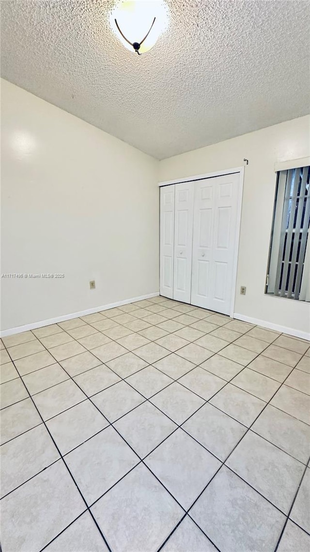 unfurnished bedroom featuring a closet, light tile patterned flooring, and a textured ceiling