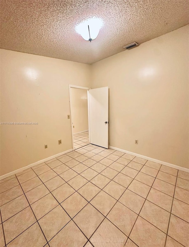 tiled empty room with a textured ceiling