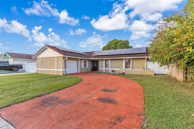 ranch-style home with a front lawn, a garage, and solar panels