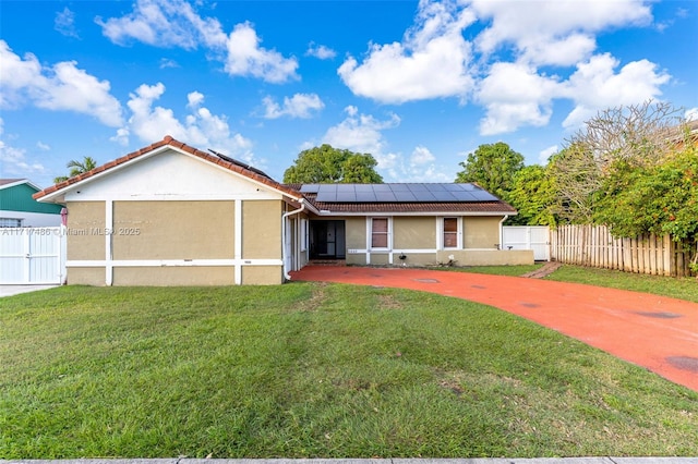 view of front of house with a front lawn and solar panels