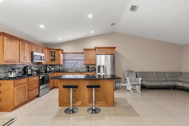 kitchen featuring a center island, stainless steel appliances, vaulted ceiling, and light tile patterned flooring