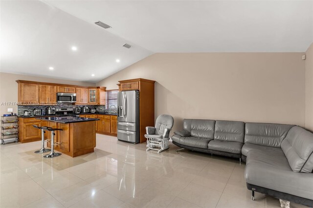 kitchen featuring a center island, lofted ceiling, light tile patterned floors, a kitchen bar, and stainless steel appliances