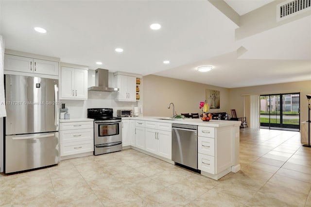 kitchen featuring white cabinets, kitchen peninsula, wall chimney exhaust hood, and stainless steel appliances