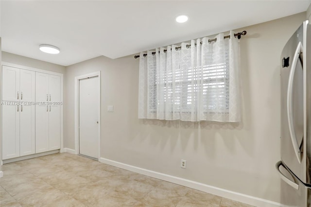 interior space featuring white cabinetry and stainless steel refrigerator