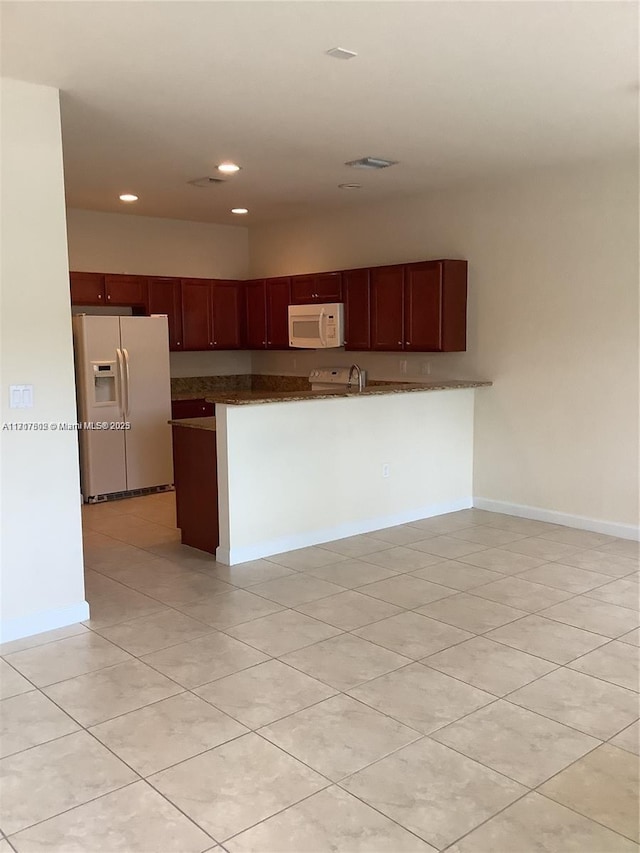 kitchen featuring kitchen peninsula, light tile patterned floors, and white appliances