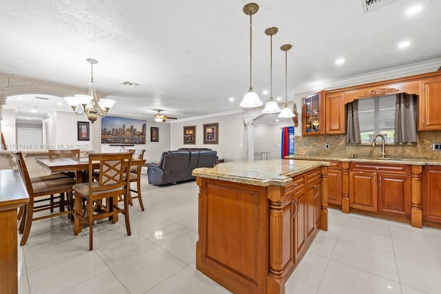 kitchen featuring sink, a kitchen island, pendant lighting, and ceiling fan with notable chandelier