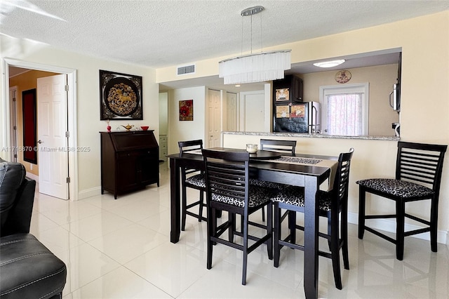 tiled dining area featuring a textured ceiling