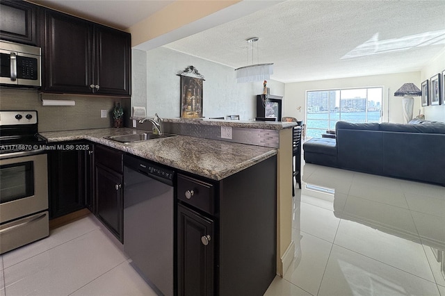 kitchen featuring light tile patterned floors, kitchen peninsula, sink, and appliances with stainless steel finishes