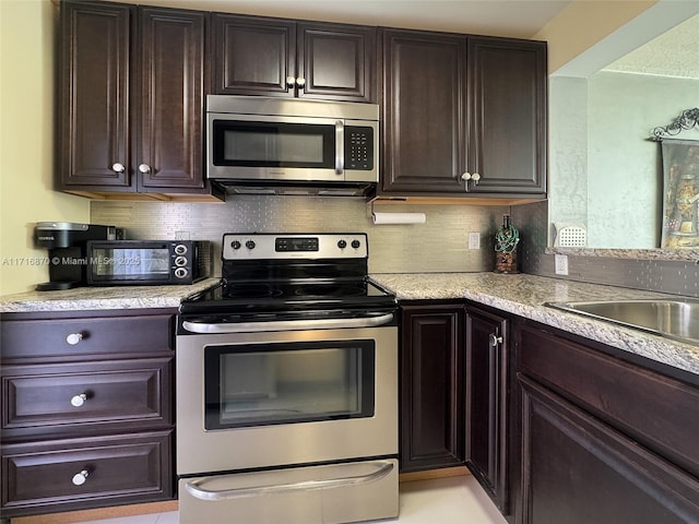 kitchen with dark brown cabinets, stainless steel appliances, and tasteful backsplash