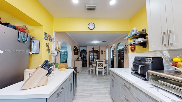 kitchen featuring a center island, light wood-type flooring, crown molding, and tasteful backsplash