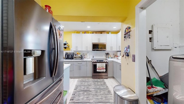 kitchen featuring washer / dryer, electric panel, white cabinetry, and appliances with stainless steel finishes