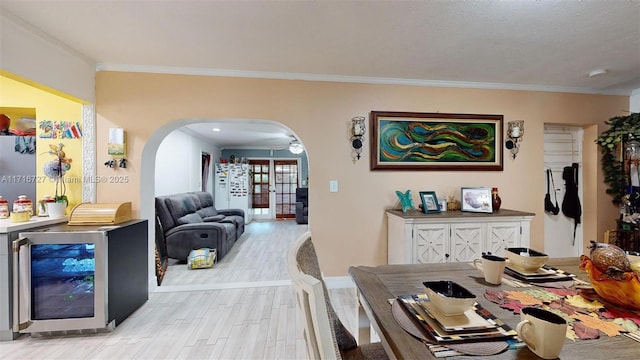 dining room featuring a textured ceiling, ceiling fan, crown molding, light hardwood / wood-style floors, and wine cooler