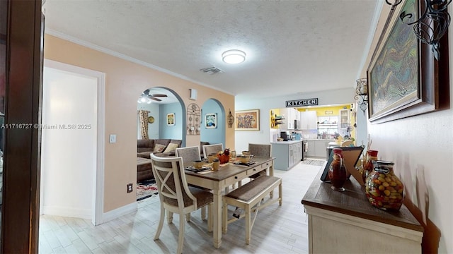 dining room featuring ceiling fan, light hardwood / wood-style floors, crown molding, and a textured ceiling