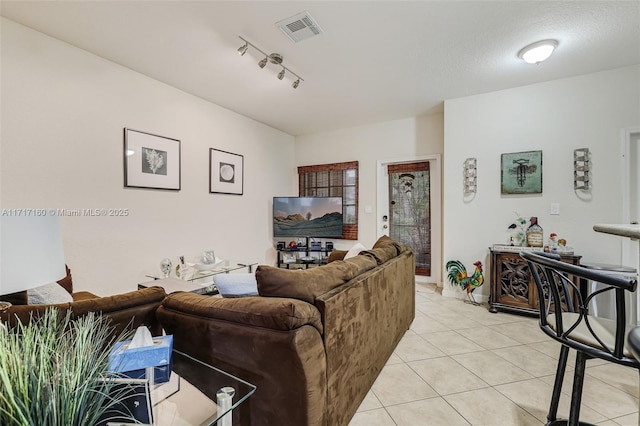 living room with a textured ceiling, light tile patterned floors, and rail lighting