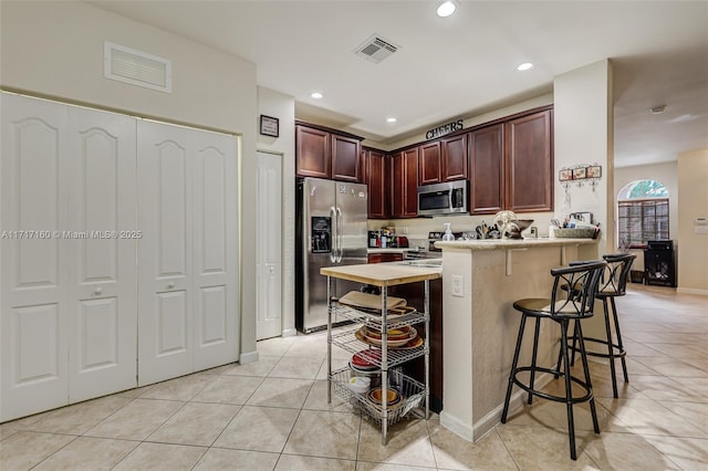 kitchen featuring light tile patterned floors, stainless steel appliances, and a breakfast bar area