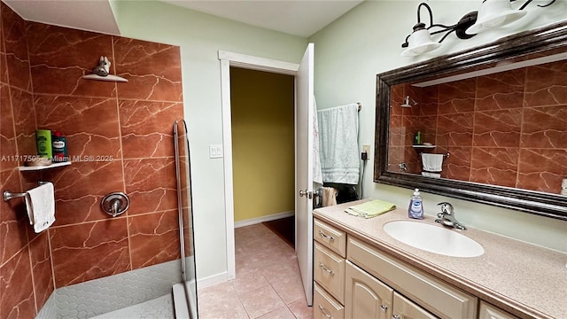 bathroom featuring tile patterned flooring, vanity, and a tile shower