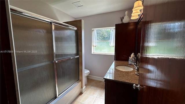 full bathroom featuring shower / bath combination with glass door, tile patterned flooring, vanity, and toilet