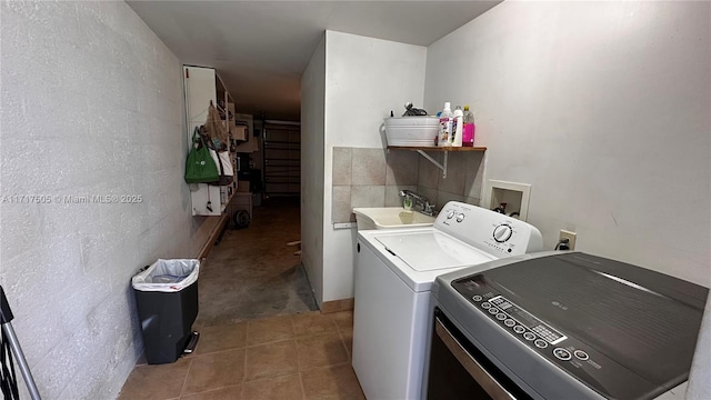 clothes washing area with tile patterned flooring, separate washer and dryer, and sink