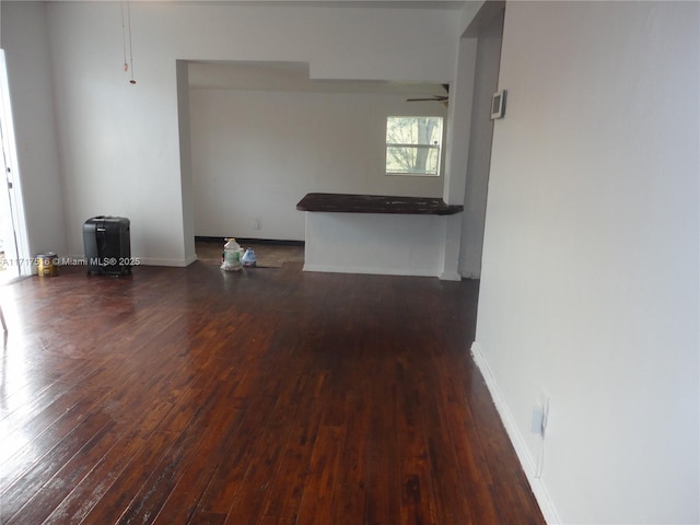 unfurnished living room with ceiling fan and dark wood-type flooring