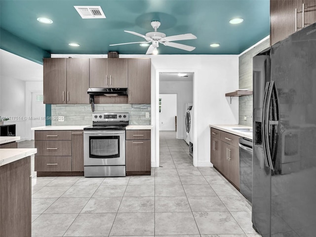 kitchen with appliances with stainless steel finishes, backsplash, ceiling fan, light tile patterned floors, and washing machine and clothes dryer