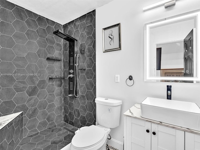 bathroom with vanity, toilet, and a tile shower