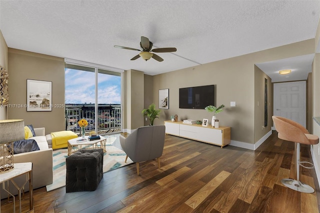 living area with a textured ceiling, wood finished floors, a ceiling fan, baseboards, and expansive windows