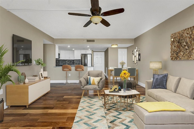 living room with baseboards, visible vents, ceiling fan, and wood finished floors