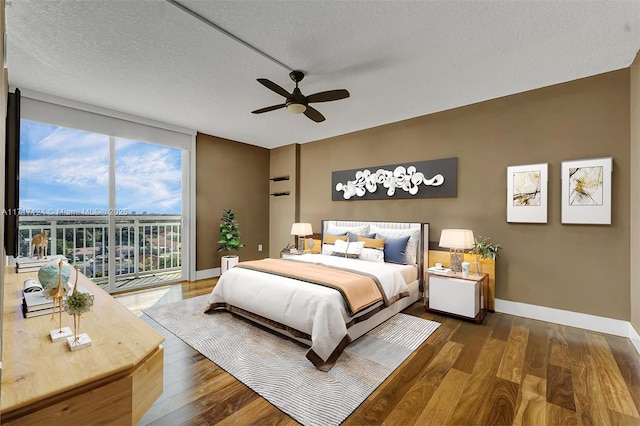 bedroom featuring access to outside, baseboards, a wall of windows, and wood finished floors