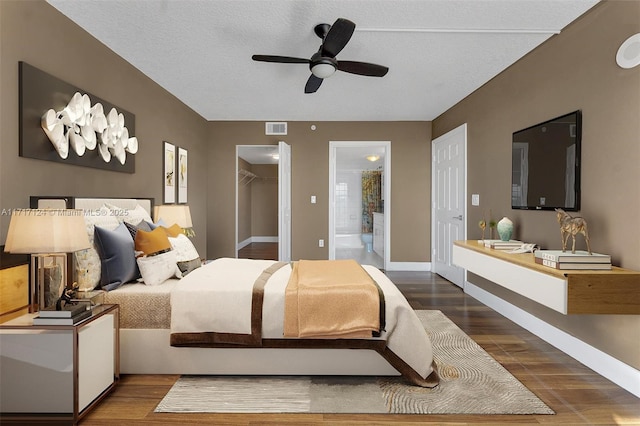 bedroom featuring a walk in closet, visible vents, connected bathroom, and wood finished floors