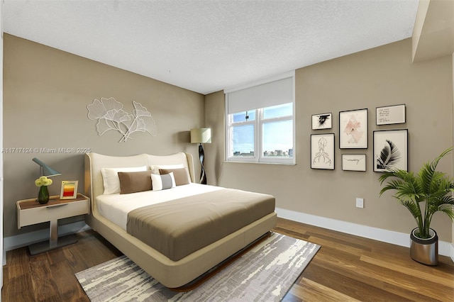 bedroom featuring a textured ceiling, baseboards, and wood finished floors