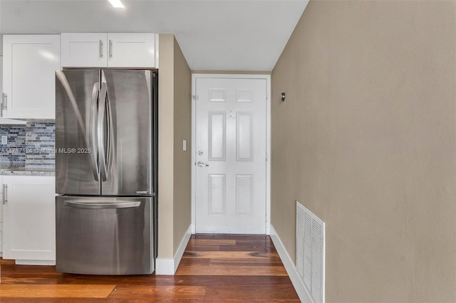 kitchen featuring freestanding refrigerator, white cabinets, visible vents, and decorative backsplash