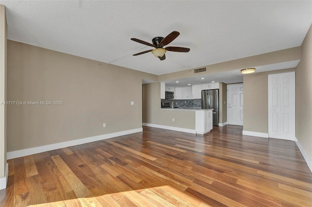 unfurnished living room with ceiling fan, dark wood-type flooring, visible vents, and baseboards