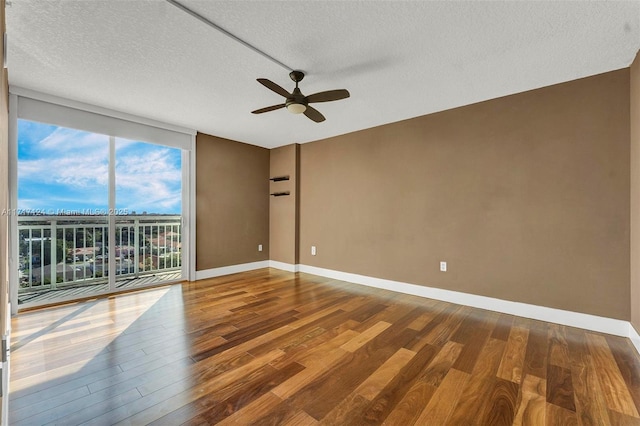 empty room featuring a wall of windows, baseboards, and wood finished floors